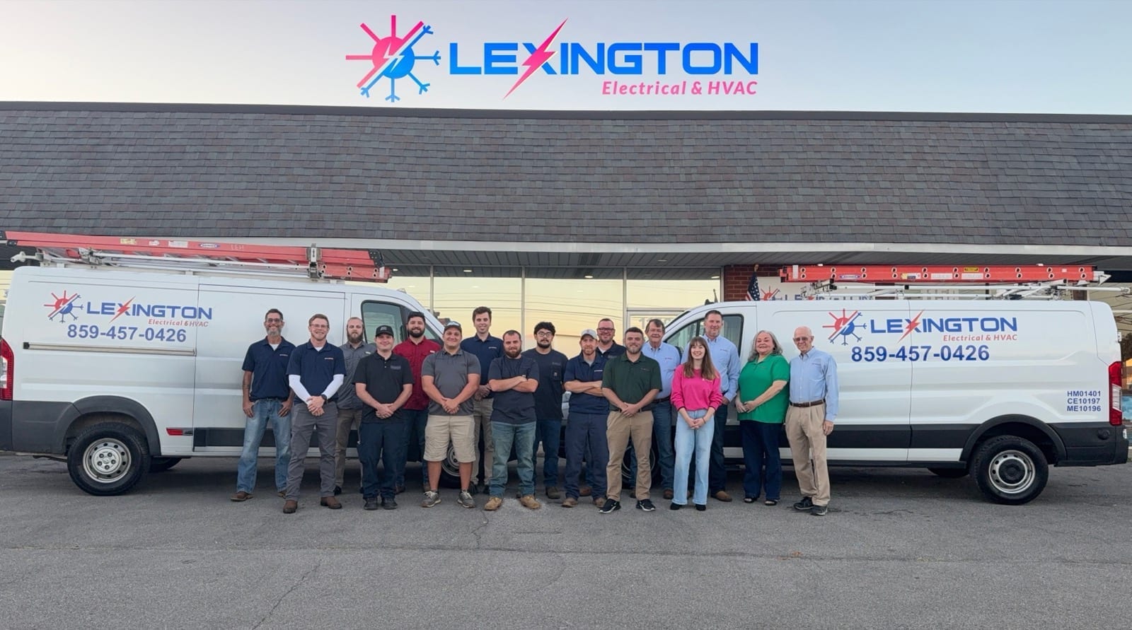 The Lexington Electrical & HVAC team posing together in front of branded service vans outside the Lexington shop